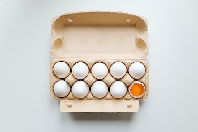 Karton mit Eiern Ein Ei ist geöffent und man sieht das Ei-Gelb