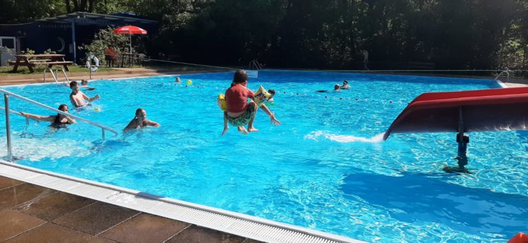 Ein Kind springt mit Anlauf in das Schwimmbecken.
