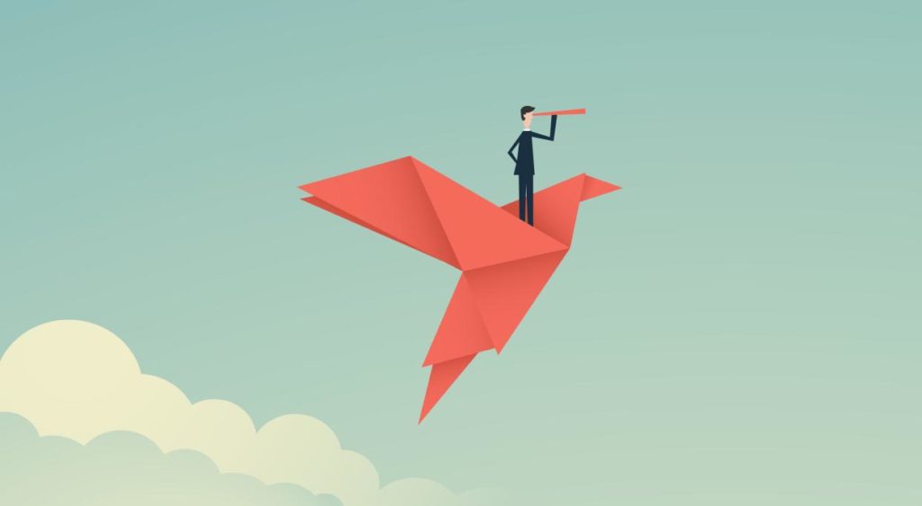 Eine Person steht auf einem Papiervogel und schaut mit einem Fernglas in die Weite