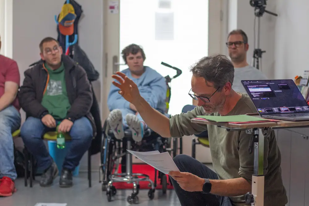 Ein Mann kniet vor Workshopteilnehmenden