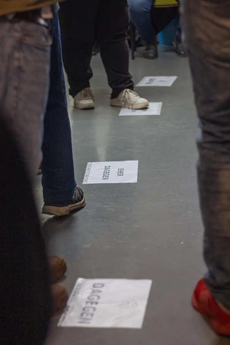 Menschen positionieren sich auf einer Streitlinie, Im Fokus, das Schild: eher dagegen